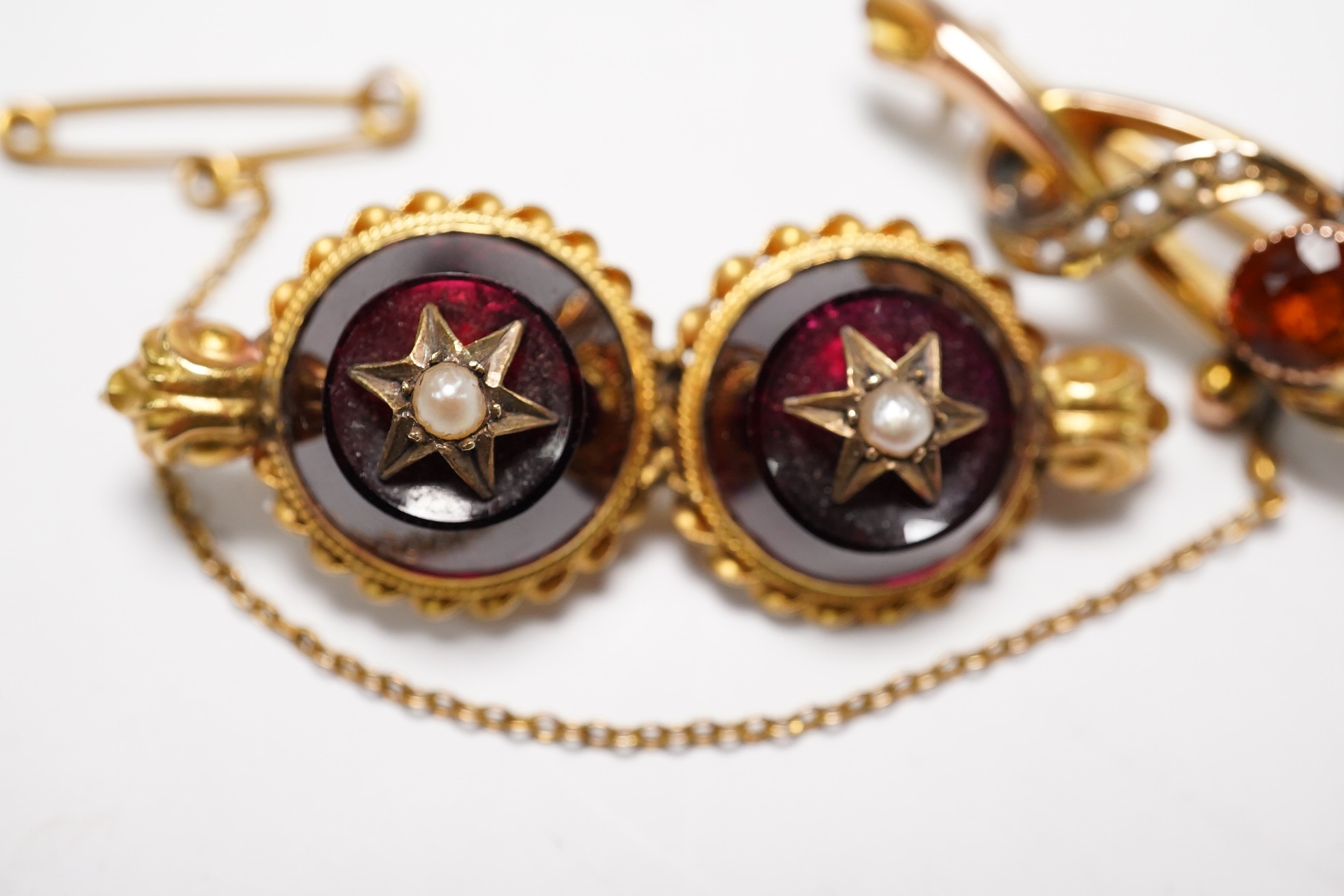 An Edwardian 9ct gold, hessonite garnet and seed pearl cluster set bar brooch, 42mm and a Victorian yellow metal, garnet and seed pearl set bar brooch, gross weight 7.3 grams, Condition - fair to good